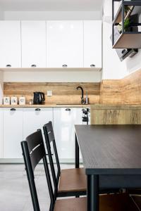 a kitchen with white cabinets and a black table and chairs at Świętego Mikołaja 14 Centrum in Głogów