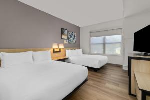 a hotel room with two beds and a flat screen tv at City Express by Marriott St. Augustine in St. Augustine