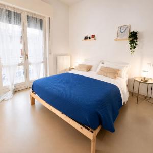 a large bed in a white room with a blue blanket at Al Carlino Verona in Verona