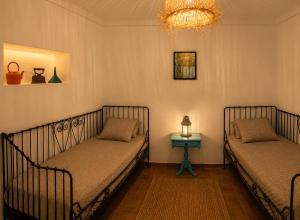 two beds in a room with a side table at Bluemoon Campinho Rooftop & BBQ near Alqueva in Campinho