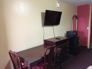 De Leon的住宿－德萊昂汽車旅館，客房设有桌子、电视和带椅子的书桌。