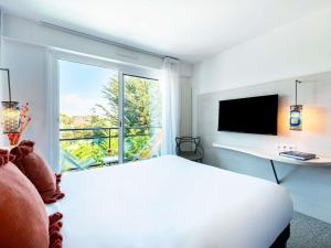 a white bedroom with a bed and a window at ibis Styles Quiberon Centre in Quiberon