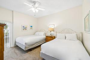 two beds in a bedroom with a ceiling fan at HP 124 Condo by 30A Escapes in Rosemary Beach +14 photos