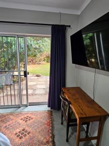 a room with a wooden table and a sliding glass door at Tarrentoela garden flatlet in Kathu