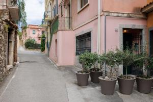 a row of potted plants on the side of a pink building at Catherine's Home Central Apartment in Taormina