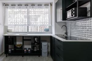a kitchen with black cabinets and a sink and a window at Catherine's Home Central Apartment in Taormina