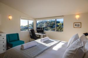 a bedroom with a bed with a desk and a chair at Miro Ridge in Palm Beach in Waiheke Island