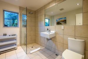 a bathroom with a toilet and a sink and a shower at Miro Ridge in Palm Beach in Waiheke Island +24 photos