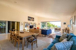 a living room with a table and a blue couch at Miro Ridge in Palm Beach in Waiheke Island