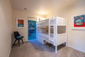 a bedroom with a bunk bed and a chair at Miro Ridge in Palm Beach in Waiheke Island