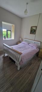 a bedroom with a bed with purple sheets and a window at Bridie's Cottage in Mullagh