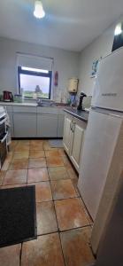 a kitchen with a white refrigerator and a tile floor at Bridie's Cottage in Mullagh