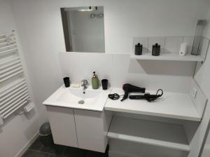 a white bathroom with a sink and a phone on it at "La maison fleurie" Sud Vendée 85 in Avrillé +16 photos