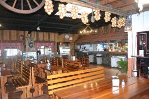 a restaurant with wooden tables and benches and a bar at Hotel Las Brumas in Cartago