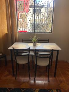 a table with four chairs and a window with a stained glass at El refugio de Lolita in Loja