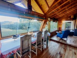 a dining room with a table and chairs and a large window at De oio no arroio in Cambará