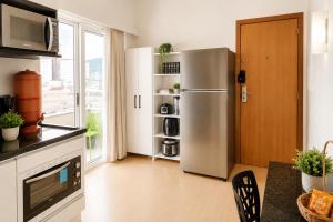 a kitchen with a stainless steel refrigerator and a window at Cinema no Quarto: Smart TV 65", Piscina e Colado no Shopping! in Joinville