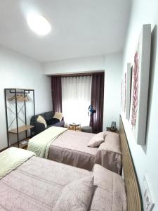 a hotel room with two beds and a couch at H & L Fogar do Camiño in Padrón