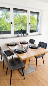 a dining room table with four chairs and two windows at ILA vacation home Memmingen in Memmingen