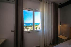 a bedroom with a window with a view of the ocean at Rumani 3 Islands Hotel in Ksamil