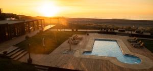 a swimming pool with a sunset in the background at Hotel Punta Sirena in Curanipe