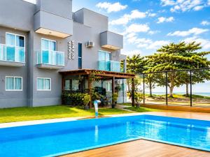 a villa with a swimming pool in front of a building at Pousada Sol & Mar Jacaraìpe ES in Serra