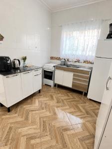 a kitchen with white cabinets and a wooden floor at Casa centro de Peruíbe in Peruíbe