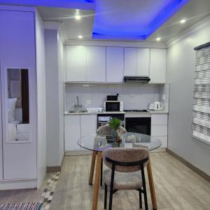 a kitchen with a glass table and some chairs at Cozy & Modern Apartment -Self Catering in Pretoria