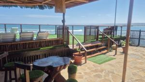 a porch with chairs and a table and the beach at Surf & Sand Lobitos in Lobitos