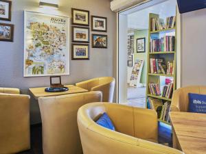 a restaurant with yellow chairs and a table and books at ibis budget Santeny in Santeny
