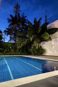 a swimming pool with palm trees next to a building at Hotel Amazonas Real in Leticia +18 photos