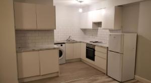 a kitchen with white cabinets and a washer and dryer at Milk Market Inn in Limerick