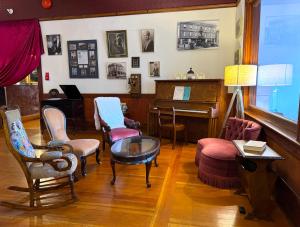 ein Wohnzimmer mit einem Klavier, Stühlen und einem Tisch in der Unterkunft Richca Heritage Hotel in Chilliwack + 45 Fotos