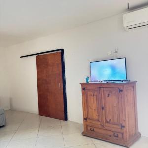a room with a tv on a wooden cabinet and a door at Casa el palmar in Guaymas