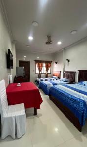 ein Hotelzimmer mit zwei Betten und einem roten Tisch in der Unterkunft Hotel Jacarandá Suites in Trinidad