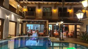 ein Schwimmbad vor einem Gebäude mit einem Restaurant in der Unterkunft Hotel Jacarandá Suites in Trinidad + 5 Fotos