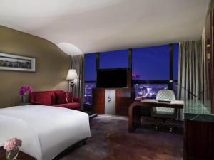 a bedroom with a bed and a desk and a television at Sofitel Kunming in Kunming
