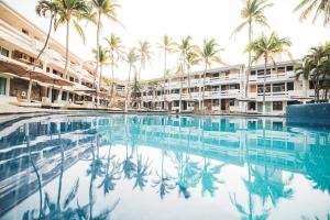 a swimming pool in front of a hotel with palm trees at Marea by Mar Paraiso Queen in Acapulco