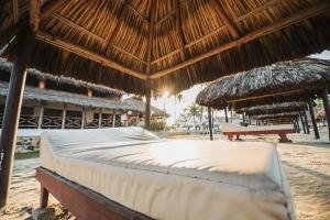 a bed under a straw umbrella on a beach at Marea by Mar Paraiso Queen in Acapulco +24 photos
