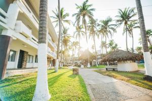 a walkway in front of a building with palm trees at Marea by Mar Paraiso Queen in Acapulco