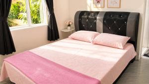 a bedroom with a bed with a black headboard and pink sheets at Villa Ar Raudhah Kuala Terengganu in Kampong Cherong Baru