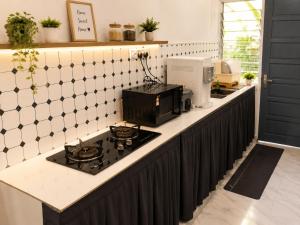 a kitchen counter with a stove and a microwave at Villa Ar Raudhah Kuala Terengganu in Kampong Cherong Baru