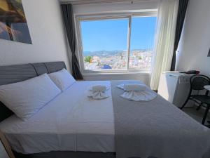 a bedroom with a white bed with a large window at Merhaba Pansiyon in Bodrum City