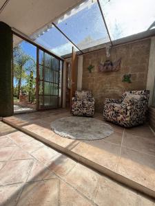 a living room with two chairs and a large window at Jardin Quinta las Fuentes in Santo Tomás Chautla
