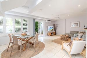 a living room with a table and chairs and a couch at Sandcastles 1, 8 Ala Moana Way - air conditioned townhouse with Wi-Fi and Complex Pool in Fingal Bay