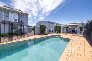 a swimming pool in front of a house at Sandcastles 1, 8 Ala Moana Way - air conditioned townhouse with Wi-Fi and Complex Pool in Fingal Bay