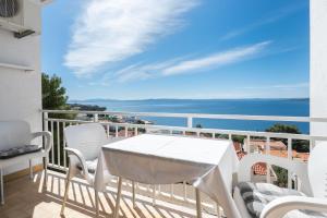 a balcony with a white table and chairs and the ocean at Apartments Vedra in Baška Voda