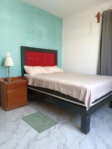 a bedroom with a bed with a red headboard and a table at Casa Lomalinda in Miahuatlán de Porfirio Díaz