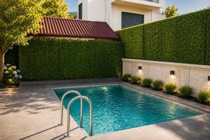 a swimming pool in front of a green hedge at Villa Jasmine in Kartepe