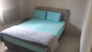 a small bedroom with a bed with blue pillows at Chacara Urbana in Navegantes +22 photos